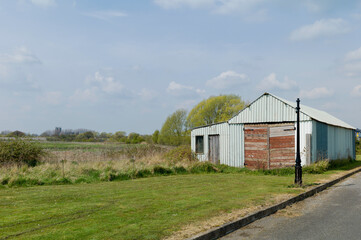 Fototapeta na wymiar Derelict corrugatied building flanking farmland left fallow in Beverley, UK.