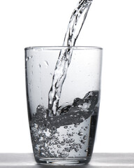 Glass of water being filled. Close up pouring clear water in transparent drinking glass over white background