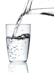 Glass of water being filled. Close up pouring clear water in transparent drinking glass over white background