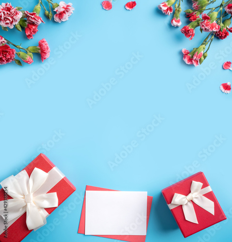 Mother's Day gift. Design concept of holiday greeting card with red carnation bouquet on bright blue table background