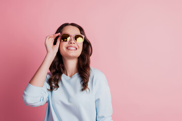 Photo of attractive woman fashion model look empty space in sunglass on pink background