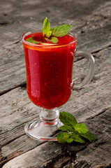 Classic raspberry tea with mint in a glass on a rustic wooden background. Photo for menus and advertising