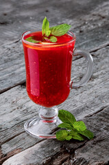 Classic raspberry tea with mint in a glass on a rustic wooden background. Photo for menus and advertising