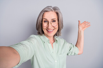 Photo of happy cheerful funky funny mature woman show demonstrate taking selfie isolated on grey color background