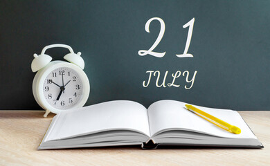 july 21. 21-th day of the month, calendar date.A white alarm clock, an open notebook with blank pages, and a yellow pencil lie on the table.Summer month, day of the year concept