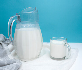 A jug and a mug of fresh milk on a white and blue background. Farm dairy product concept. World Milk Day. Healthy diet. copy space for text