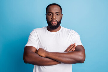 Serious african businessman standing with arms folded on blue wall