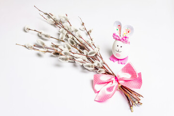 Sprig of willow isolated on white background with handmade funny bunny from the egg