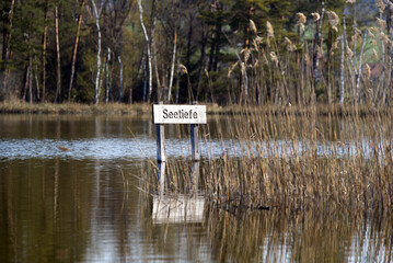Wooden sign with text lake depth at nature reserve Katzensee (German, translation is cat lake) at...