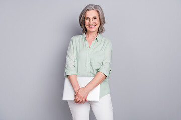 Photo of mature smiling good looking smart intelligent businesswoman hold laptop isolated on grey...