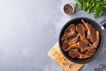 Marinated lamb meat with spices on a frying pan. Top view, text space