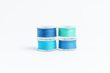 Group of mixed colourful blue spools of cotton thread displayed horizontally, isolated on white,...
