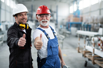 Portrait of workers in factory. Colleagues showing thumbs up.