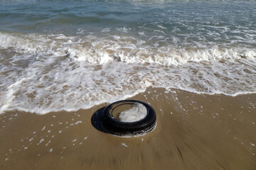 Used car tyre on the sea beach.
