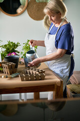 Side view of woman watering freshly sown seeds