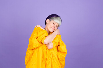 Stylish european woman on purple background self care hugging herself with smile and closed eyes