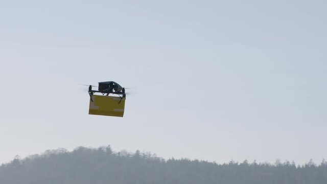 delivery drone carrying parcel flying across the blue sky