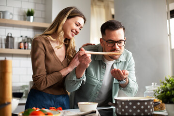Happy smiling couple cooking together. Boyfriend and girlfriend preparing delicious food..