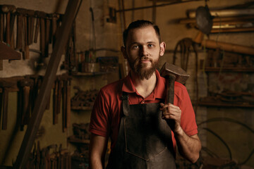 Fototapeta na wymiar Blacksmith with hammer in workshop closeup portrait