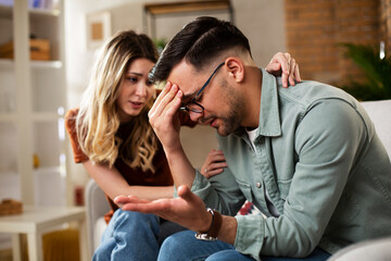 Young man having a problem. Girlfriend comforting her sad boyfriend