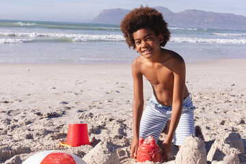 African american boy having fun playing with sand at the beach