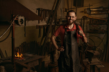 Blacksmith with hammer in workshop portrait smiling