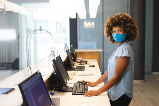 Portrait of woman wearing face mask working as receptionist in hotel - Powered by Adobe