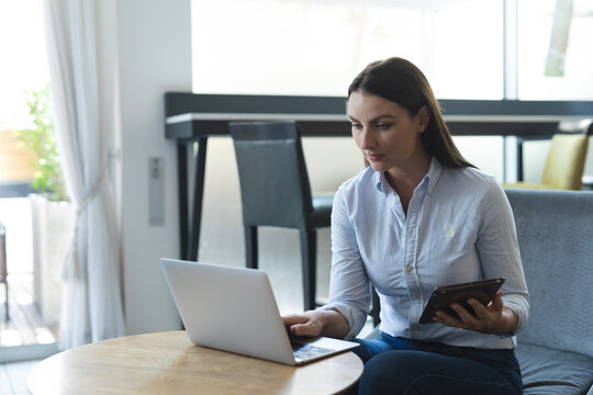 Portrait of caucasian businesswoman sitting on sofa working with laptop