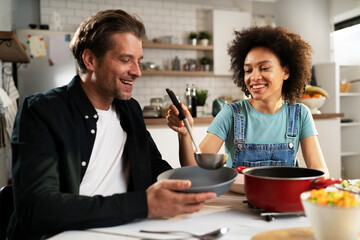 Boyfriend and girlfriend eating lunch together at home. Husband and wife enjoying in delicious food..