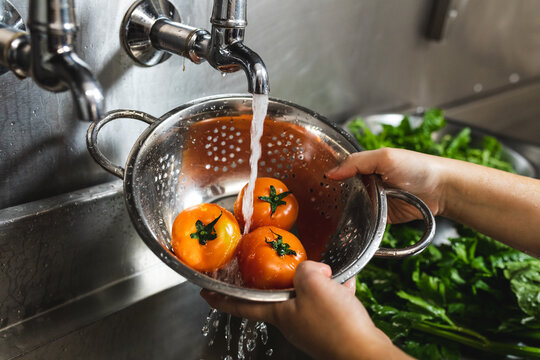 Close up of hands of person washing tomatoes with water