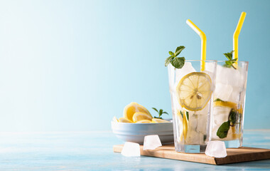 ingredients for lemonade or mojito cocktail with lemon and mint, cold refreshing drink or beverage with ice on blue background. Copy space
