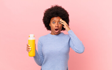 afro woman looking happy, astonished and surprised, smiling and realizing amazing and incredible...