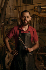Fototapeta na wymiar Blacksmith with metal tongs in smithy portrait
