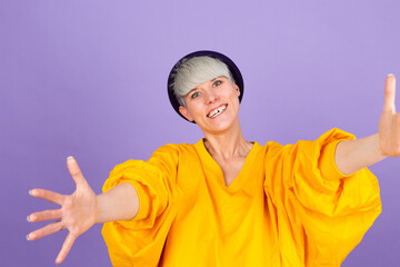 Stylish european woman on purple background looking at the camera smiling with open arms for hug