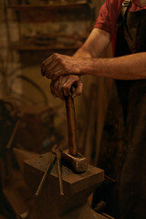 Blacksmith hold hammer on anvil in smithy