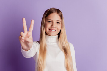 Photo of little lady show v-sign toothy smile wear white pullover posing on purple background