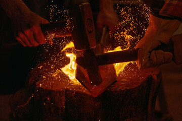 Blacksmiths hit molten metal with hammers close up