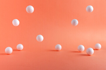White small balls falling on the bright orange surface