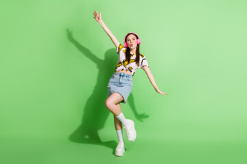 Full length photo of happy young woman dance sing good mood wear headset isolated on green color background