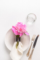 Elegance romantic table setting with pink peony flowers on a white table. View from above. Vertical format.