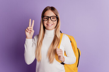 Young woman showing two fingers peace gesture carry backpack