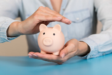 Piggy bank in hand on blue background, space for text. Finance, saving money. Business to success...