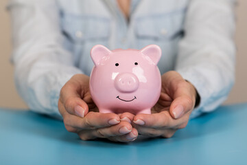 Piggy bank in hand on blue background, space for text. Finance, saving money. Business to success...