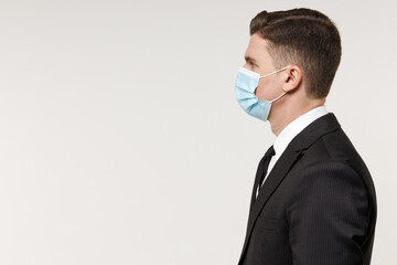 Side view oung employee business corporate lawyer man in classic formal black grey suit shirt tie sterile face mask coronavirus covid19 pandemic quarantine work in office isolated on white background