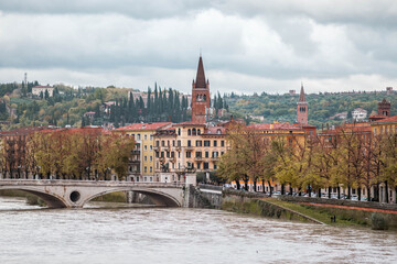 Panoramic view to Bridge Ponte Pietra in Verona on Adige river, Veneto region, Italy. Sunny summer day panorama and blue dramatic sky with clouds. Ancient european italian terracotta color houses.