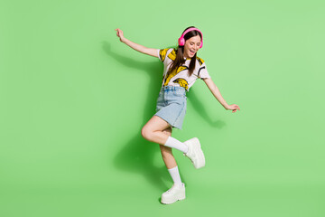 Full body photo of attractive young positive woman listen music dance isolated on green color background