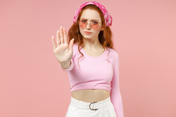 Obraz na płótnie Canvas Young sad serious strict woman 20s wearing rose clothes bandana glasses doing stop palm gesture refusing saying no isolated on pastel pink color background studio portrait People lifestyle concept