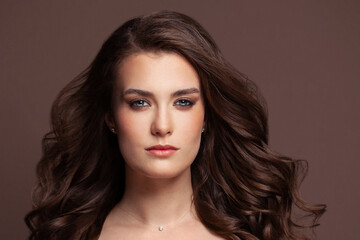 Healthy brunette woman with brown curly hair on brown background