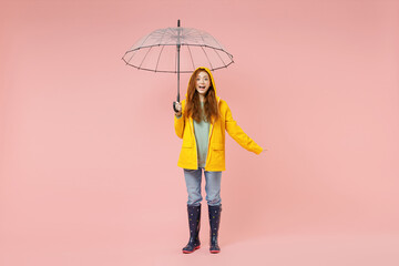 Full length redhead happy young woman in yellow waterproof raincoat hood outerwear hold transparent...