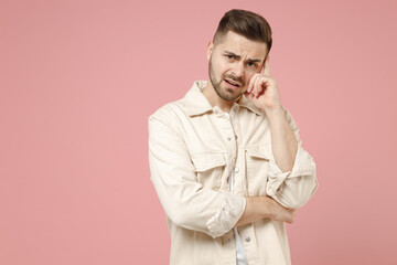 Young puzzled pensive thoughtful sad trendy caucasian man 20s wearing jacket white t-shirt prop up chin look camera isolated on pastel pink color background studio portrait People lifestyle concept